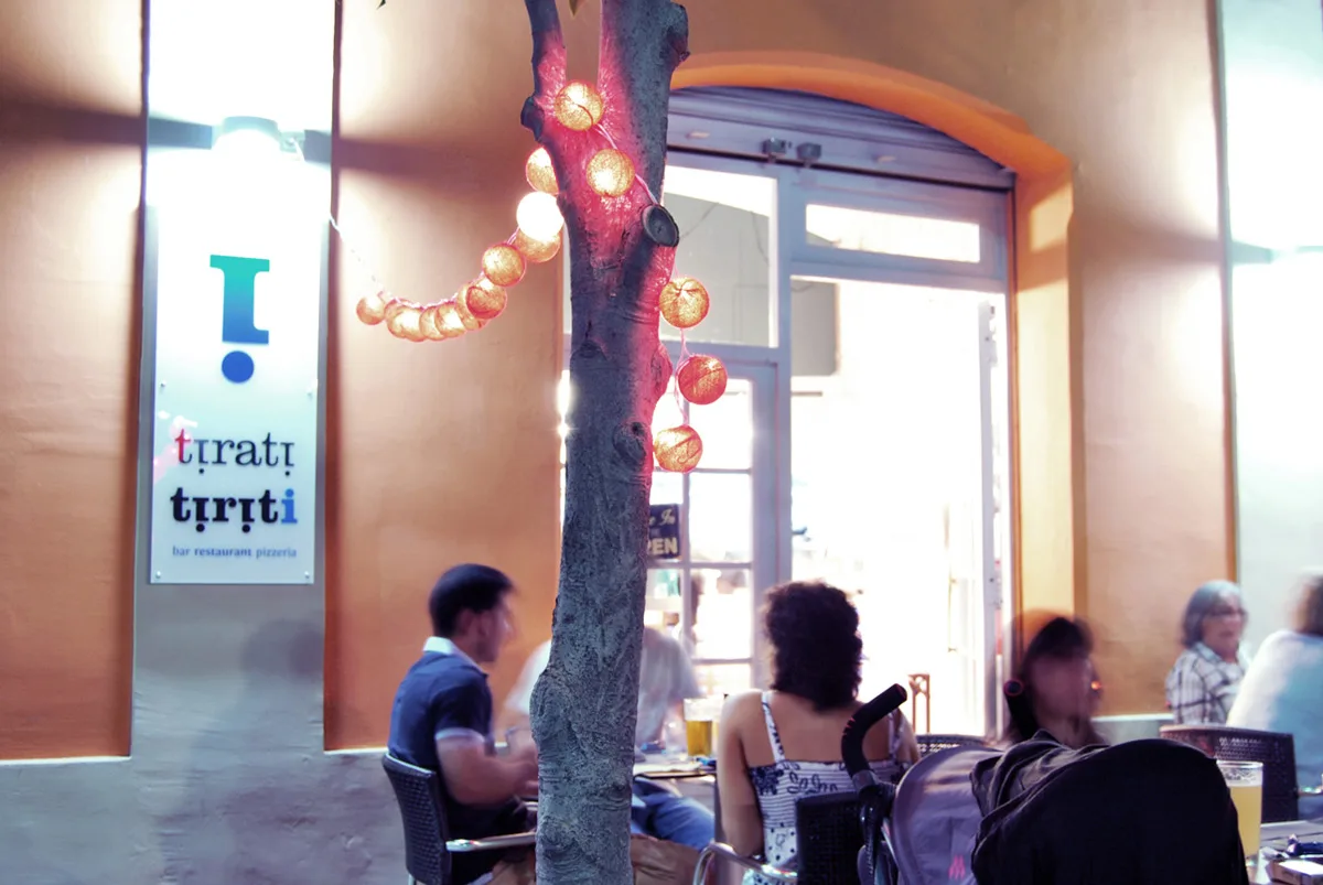 Entrada del Tiriti guarnida amb garlandes de llum i gent sopant a la terrassa